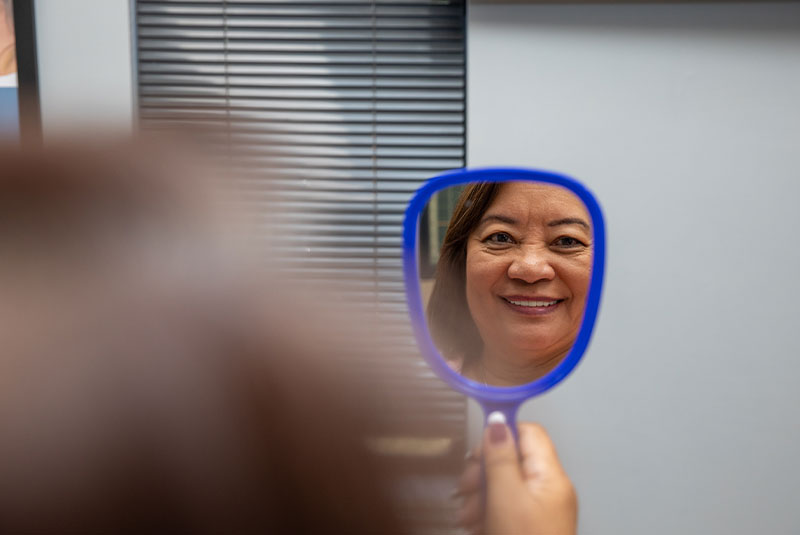 Patient looking into mirror after Crowns Procedure